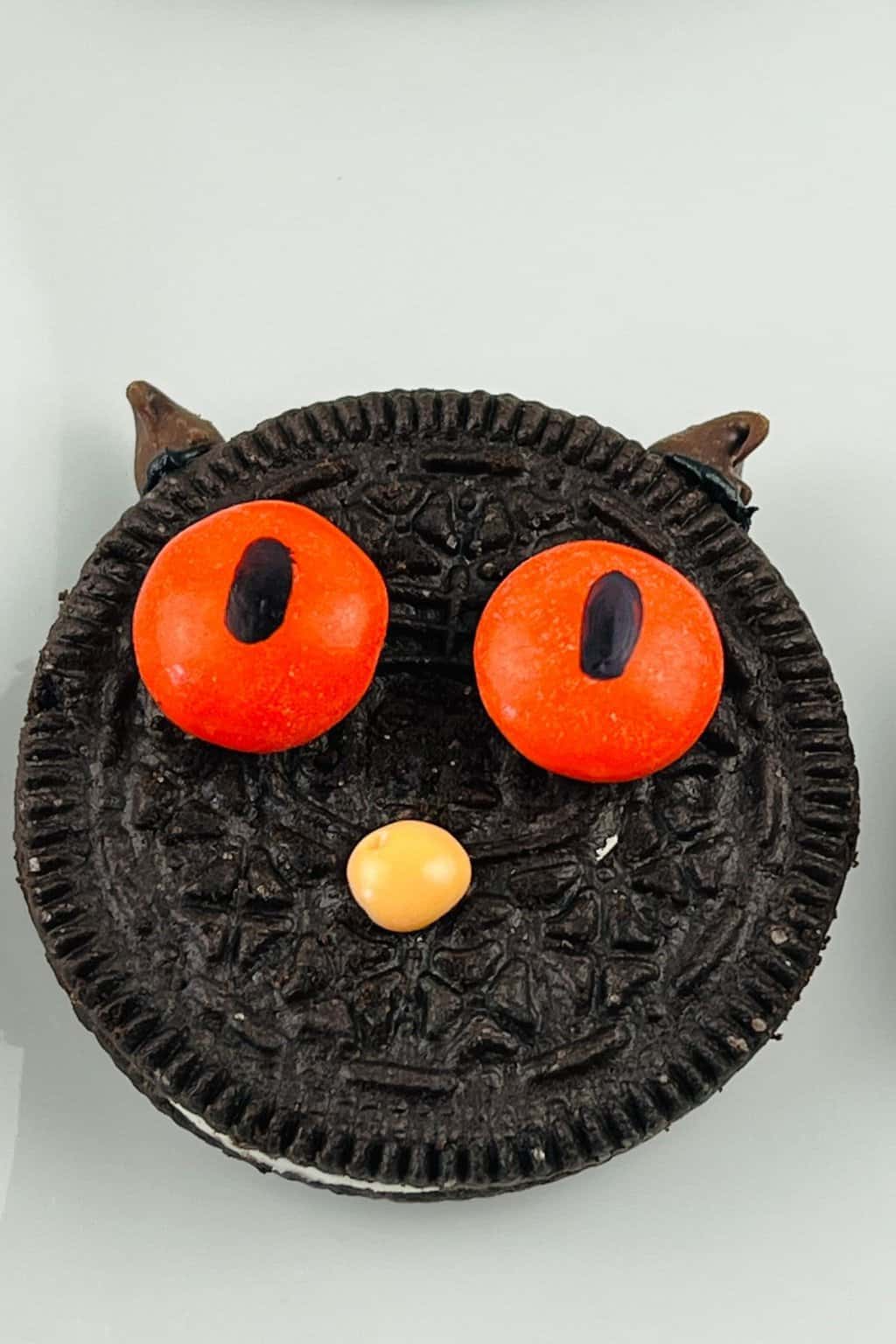 Oreo cat cookie for Halloween with orange eyes.