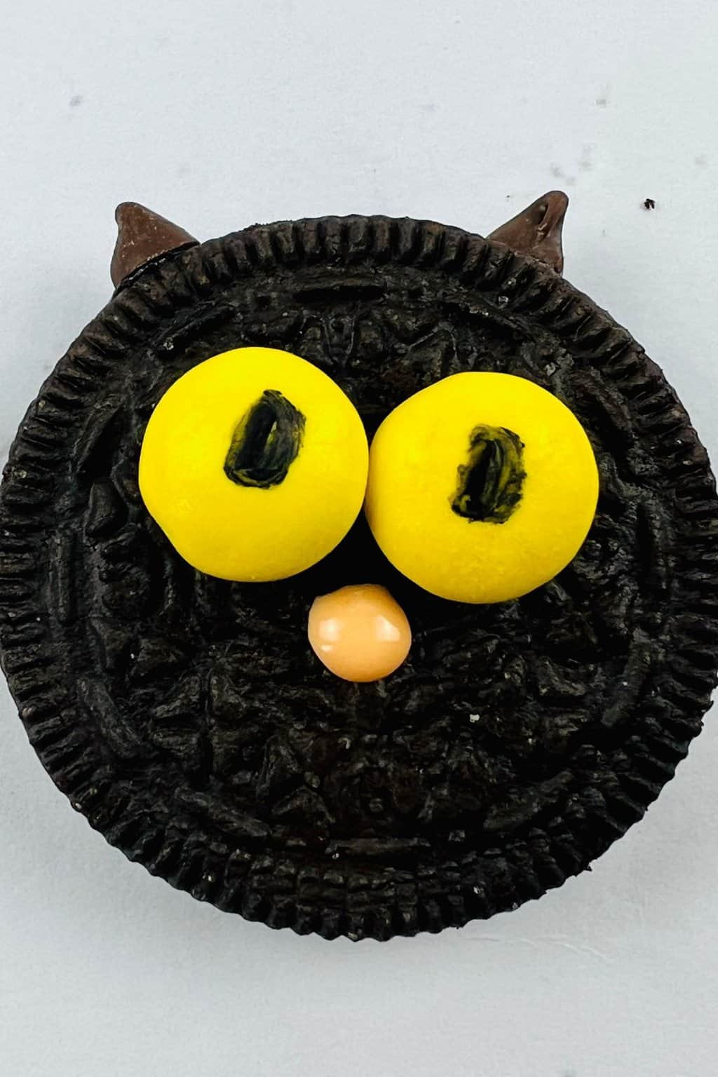 Oreo cat cookie for Halloween with yellow eyes.