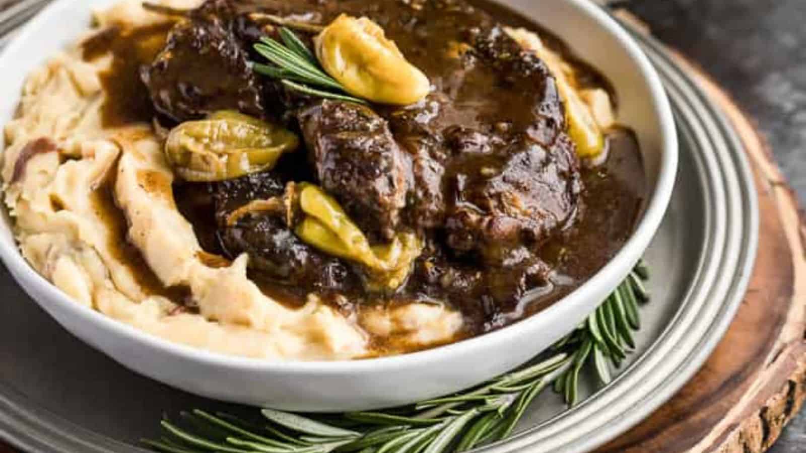 A plate of pot roast with peppers, serve over mashed potatoes.