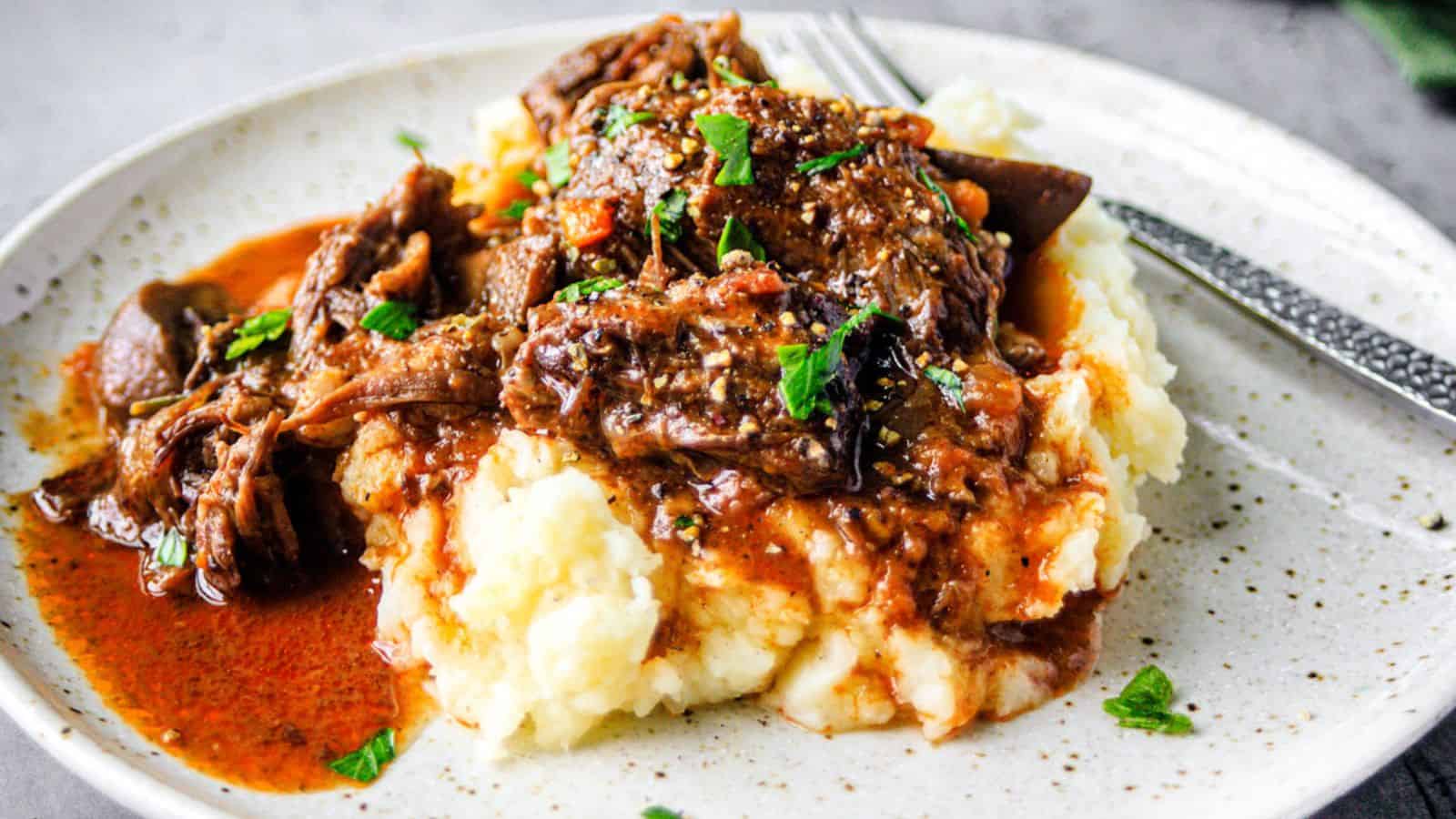 A plate of beef bourguignon over potatoes.