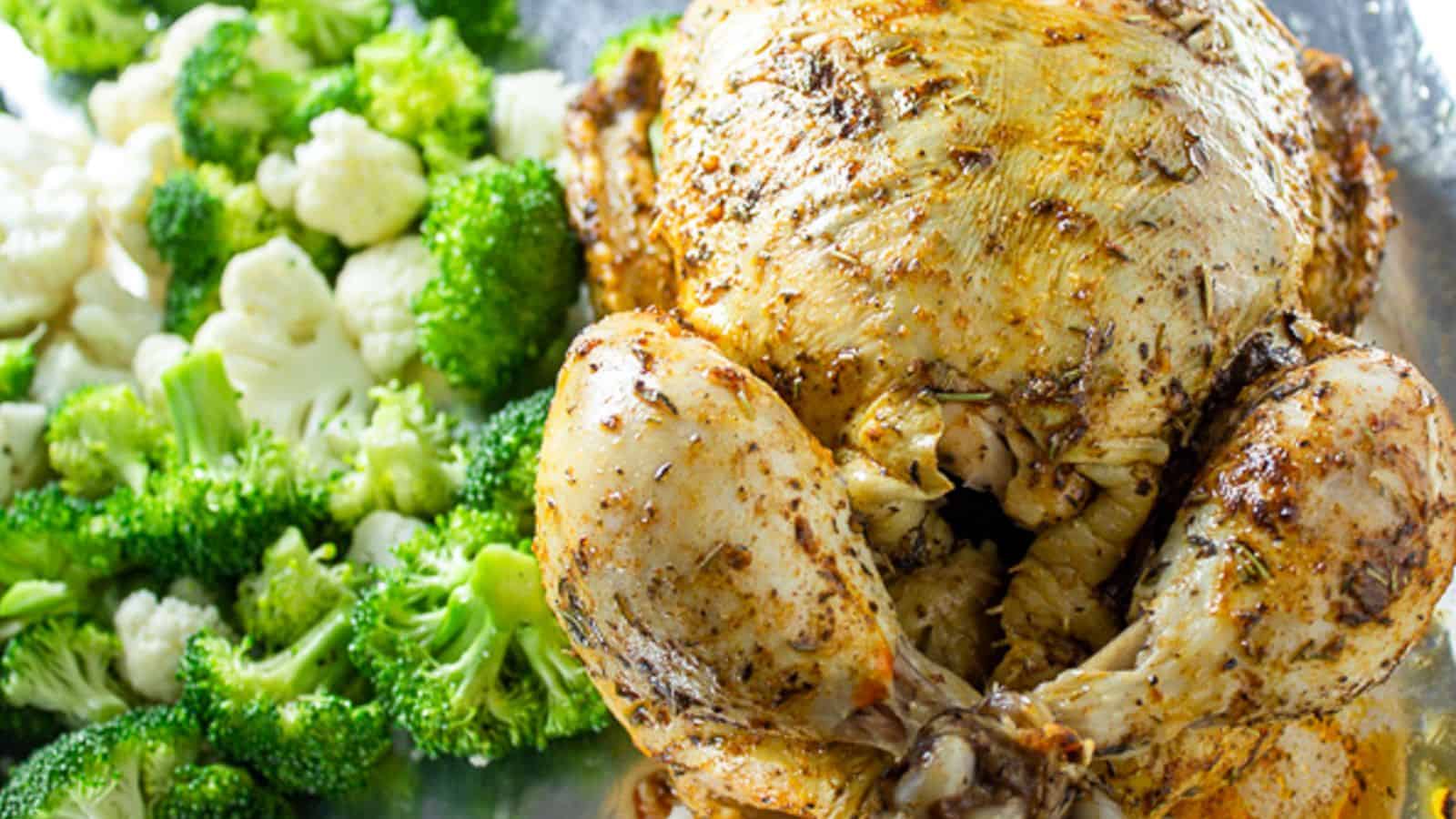 A whole roasted chicken with veggies on the side.