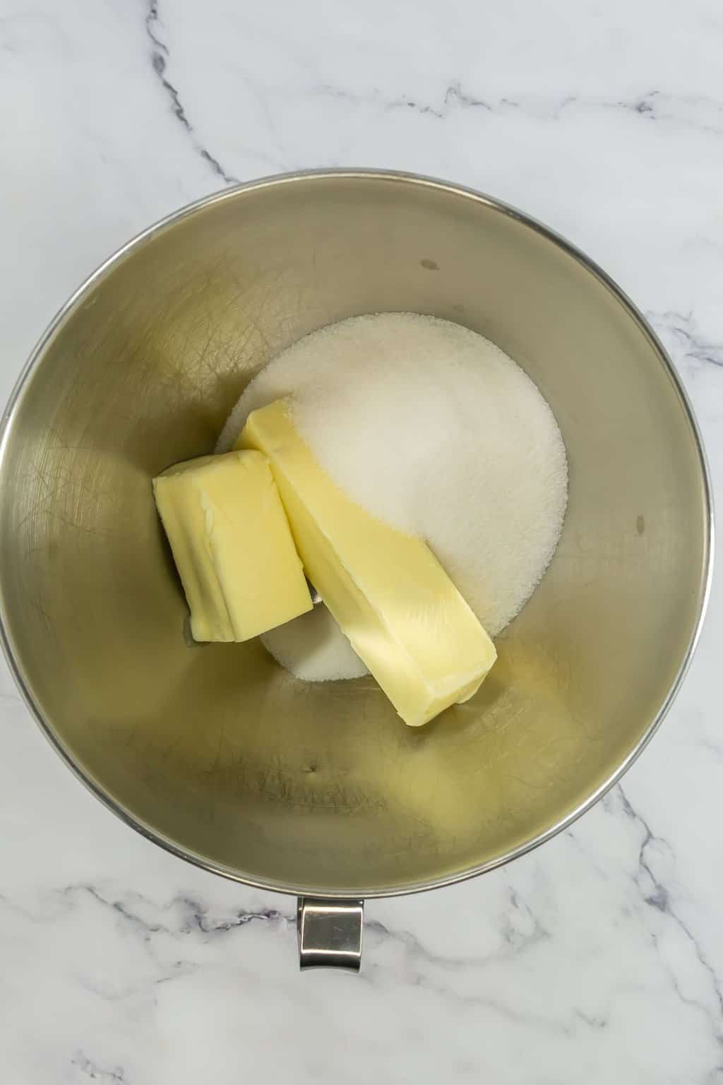 Butter and sugar added to a mixing bowl.