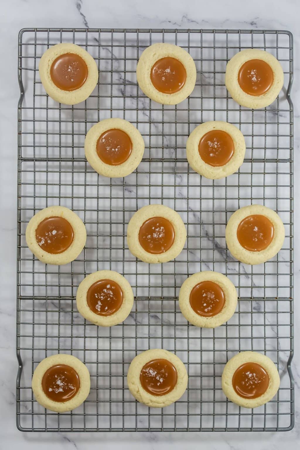 Caramel and salt added to the cookies on a cooling rack.