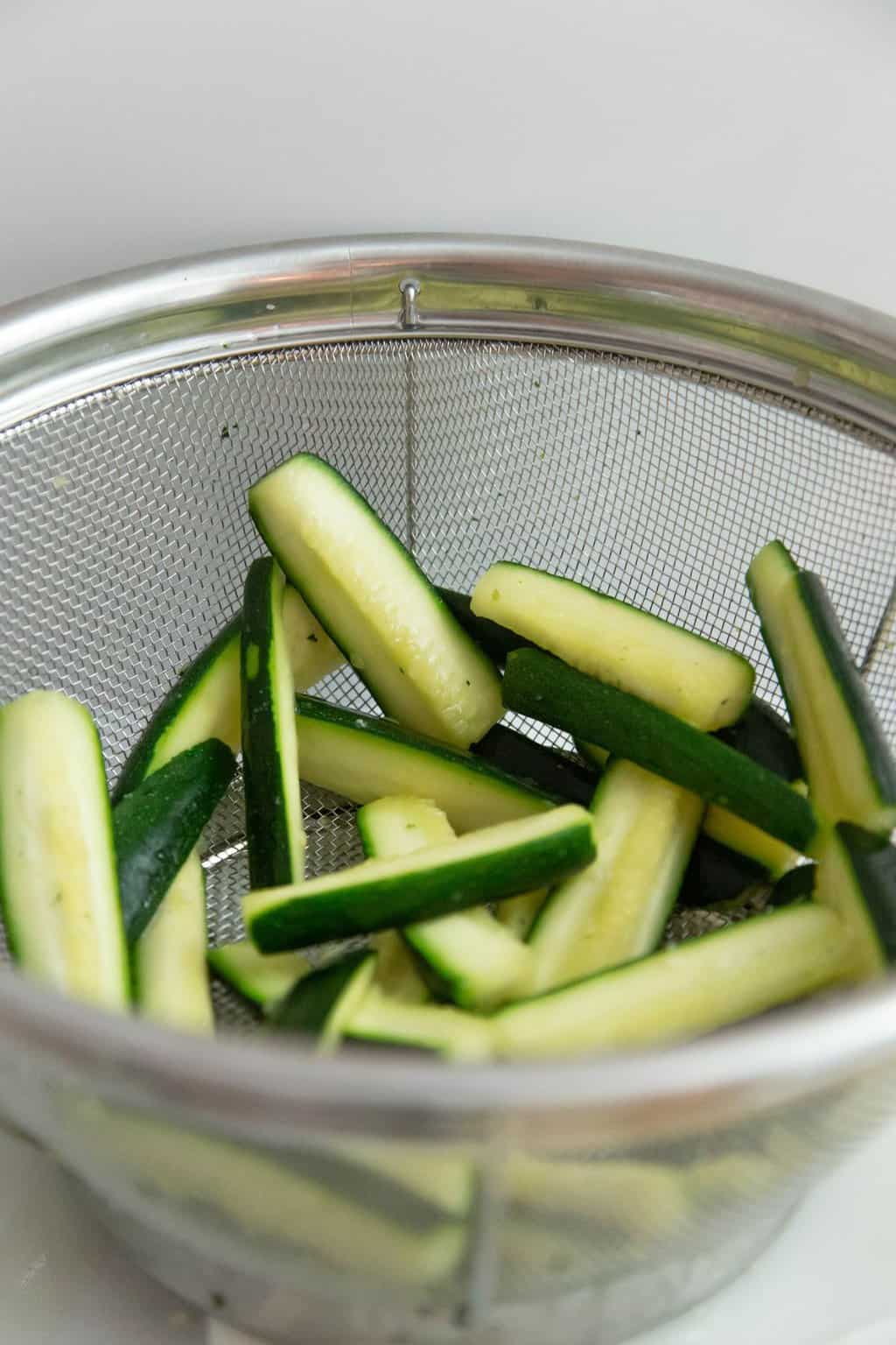 Zucchini sitting in strainer with salt.