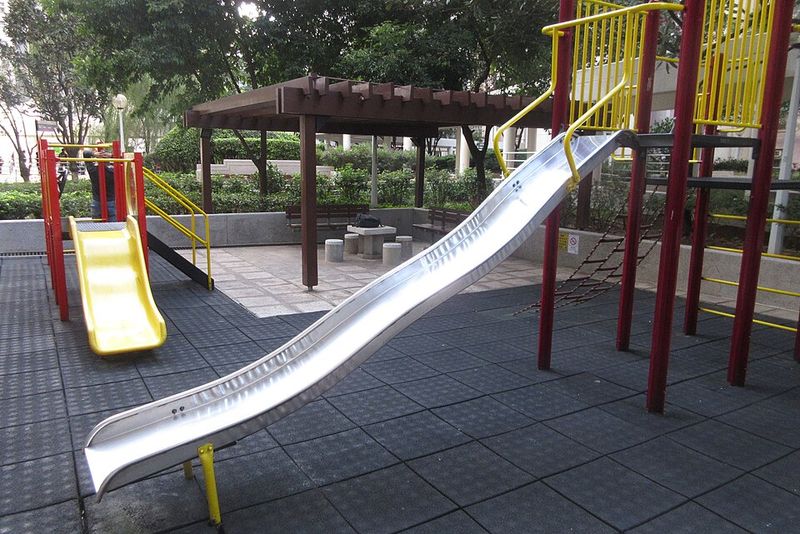 Tall Metal Playground Slides Over Bare Concrete